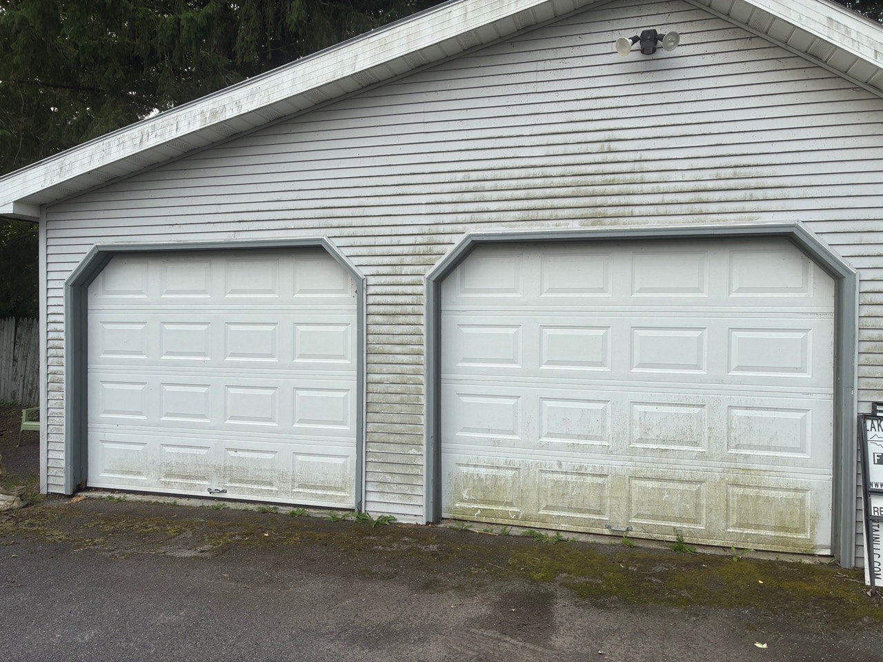 Garage siding and doors with dirt and organic buildup before cleaning